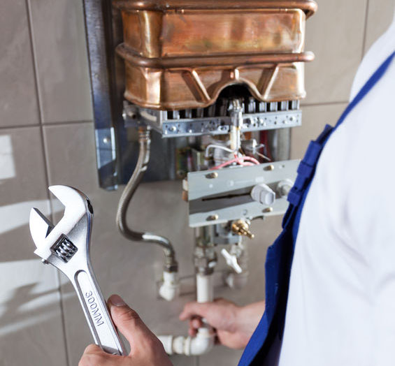 Repairman fixing a gas water heater with a wrench