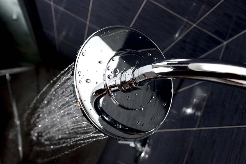 closeup of chrome shower head with flowing water
