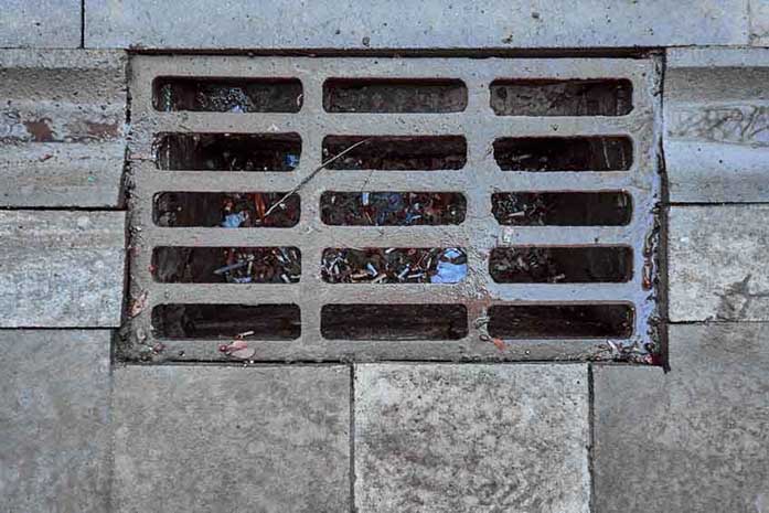 Sewage grate on the road with garbage