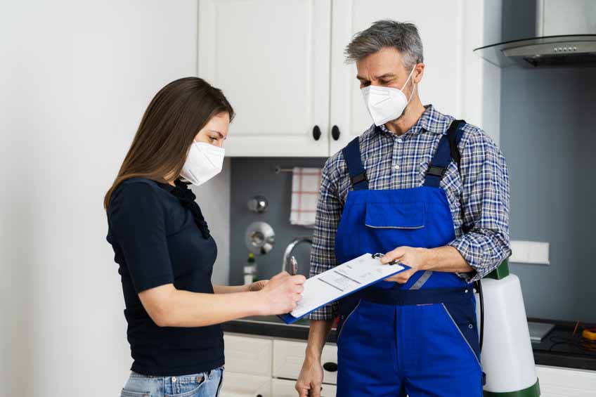 Handyman Plumber And Customer With Service Contract Handyman Plumber And Customer With Service Contract On Clipboard In Face Mask