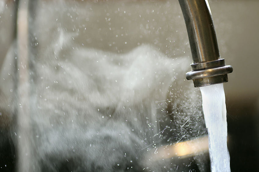 Hot Steaming Water Running from Kitchen Faucet Hot steaming running tap water is pouring out of a stainless steel kitchen faucet.