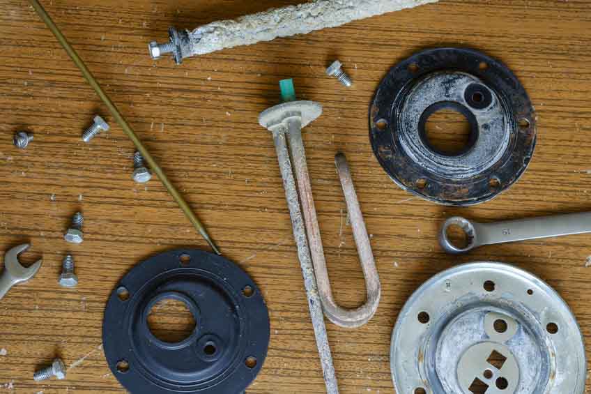Details of a disassembled water heater. Anode, heating element, temperature sensor, gaskets, flange. Qualified repair of a water heater. Commercial services for the repair of household appliances. View from above.