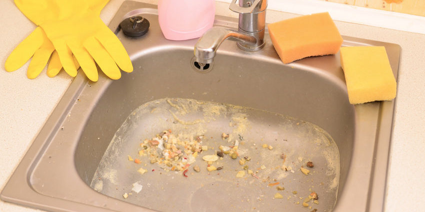 Close up on dirty clogging kitchen sink drain. Blur and selective focus of sink hole clogging up with food particles
