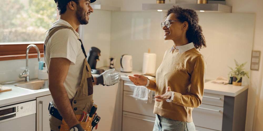 contractor speaking with a homeowner next to exposed piping