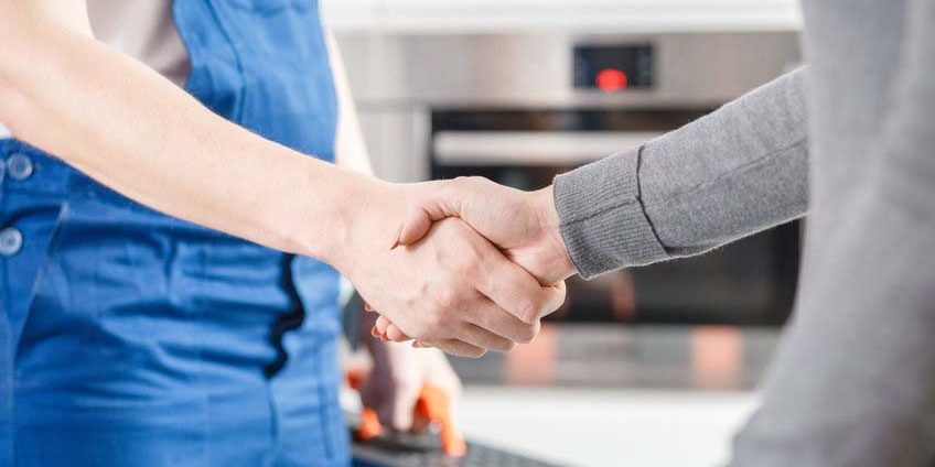 Specialist shaking hands with housewife Close-up of hydraulic specialist in blue overalls shaking hands with a housewife after repairing a glitch