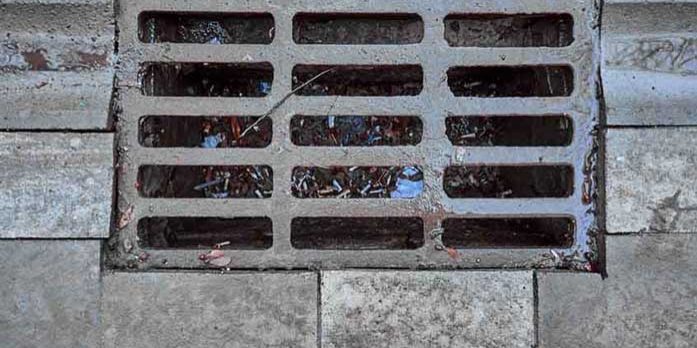 Sewage grate on the road with garbage