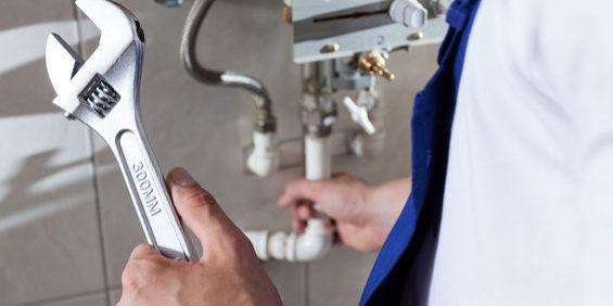 Repairman fixing a gas water heater with a wrench
